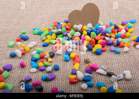 Herz aus Papier inmitten der bunten Steinchen auf Leinwand Boden Stockfoto