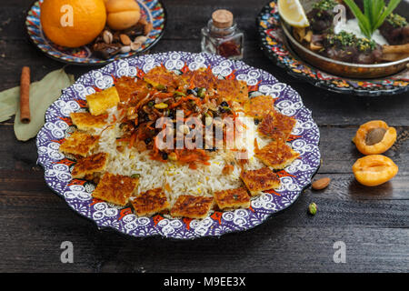 Iranische Pilav mit Orangenschale, Nüssen und Rosinen, auf einem traditionellen Platte Stockfoto