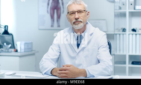 Erfahrene Grauhaariger Leitender Arzt und lächelnd in die Kamera schaut. Portraitfotos in der modernen und hellen Büro. Stockfoto