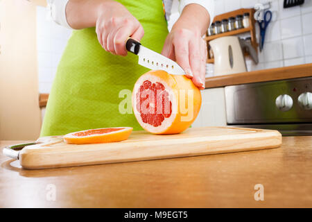 Weibes Hände schneiden frische Grapefruit auf Küche Stockfoto