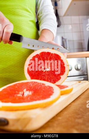 Weibes Hände schneiden frische Grapefruit auf Küche Stockfoto