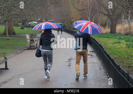 Ein paar Spaziergang durch St. James's Park mit Union Jack Schirme an einem kalten, grauen, nassen Tag in London. Stockfoto