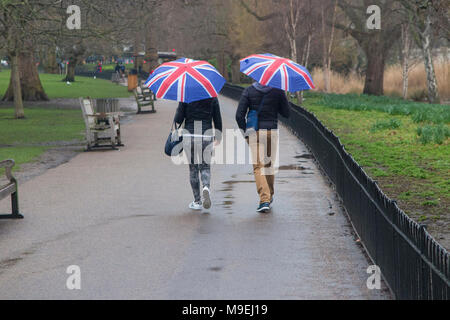 Ein paar Spaziergang durch St. James's Park mit Union Jack Schirme an einem kalten, grauen, nassen Tag in London. Stockfoto