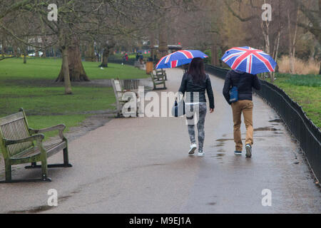 Ein paar Spaziergang durch St. James's Park mit Union Jack Schirme an einem kalten, grauen, nassen Tag in London. Stockfoto