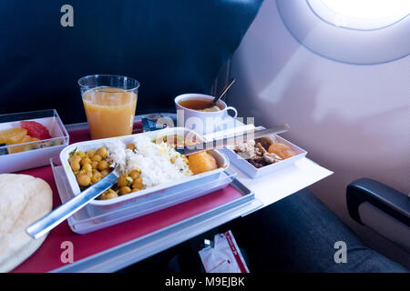 Foto von Essen an Bord der Economy Class Flugzeug auf dem Tisch. Satz von asiatischer Küche. Die Mahlzeiten auf der Klapptisch vor dem Flugzeug Fenster Stockfoto