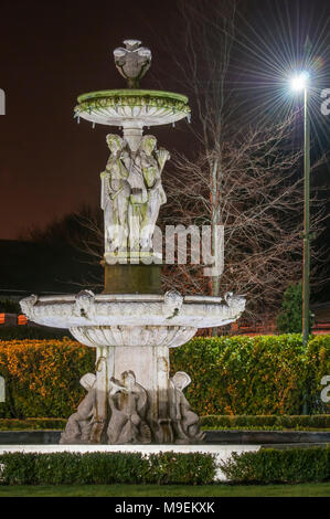 Großer Stein Wasser Brunnen in einem formalen Garten bei Nacht. Stockfoto