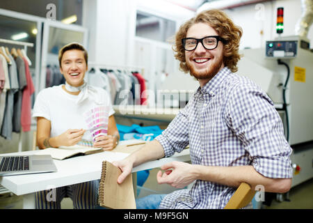 Portrait von Happy Designer am Tisch sitzen und Planung neue Kollektion Stockfoto