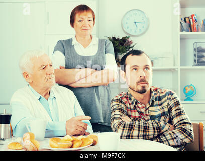 Ältere Großeltern sprechen, ernst und beauftragt Enkel in Anwesenheit von Großmutter Stockfoto