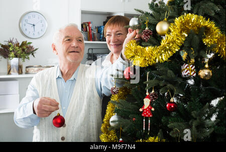 Im Alter von Mann und Frau, Dekorationen auf Weihnachtsbaum zu Hause Stockfoto