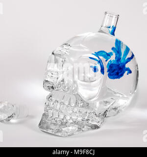 Glas Schädel mit blauer Tinte Tropfen in Wasser, Alkohol Stockfoto