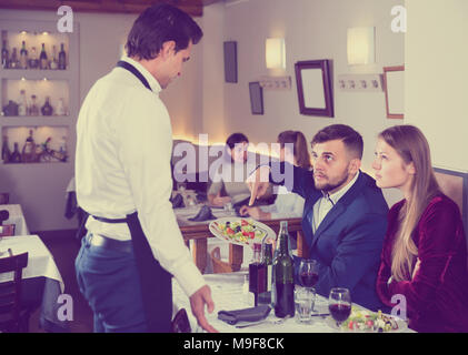 Verärgert die Gäste in Konflikt mit Kellner wegen der schlechten Qualität der Speisen im Restaurant Stockfoto