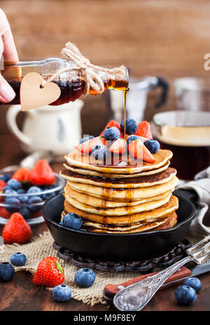 Stapel von frisch zubereiteten Banana Pancakes mit frischen Beeren und Ahornsirup zum Frühstück Stockfoto