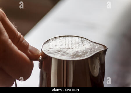 In männlichen Händen Milchkännchen mit Schlagsahne Milch, close-up. Stockfoto