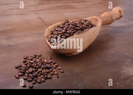 Kaffeebohnen in eine hölzerne Schaufel auf dunklem Stein Tabelle. Stockfoto