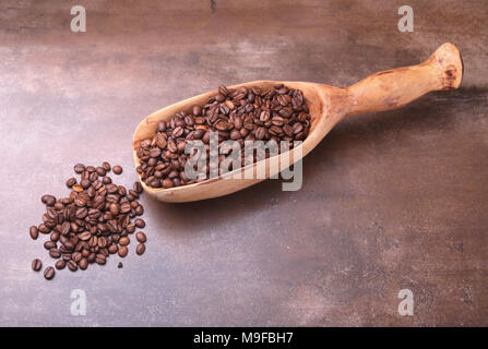 Kaffeebohnen in eine hölzerne Schaufel auf dunklem Stein Tabelle. Stockfoto