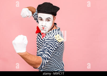 Er sah einen Aufkleber auf dem Rücken, wurde wütend, bereit zu kämpfen. Clown, Artist, Mime. Studio shot, rosa Hintergrund Stockfoto