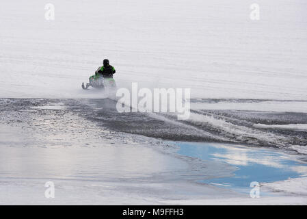 Snowmobile Racing über eine offene Patch von Wasser auf der See angenehm, NEW YORK in den Adirondack Mountains mit kopieren. Stockfoto