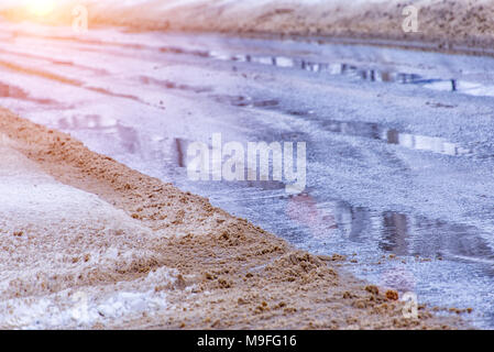 Straße mit Pfützen in schmutziger Schnee, Frühling Tauwetter Stockfoto