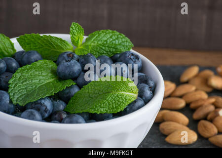 Bereit für den Sommer Obst? Raw, süßen Heidelbeeren in einer weissen Schüssel schön aussehen und sogar besser schmecken. Zitrone und Minze hinzufügen einen hellen Kontrast der Farben. Stockfoto