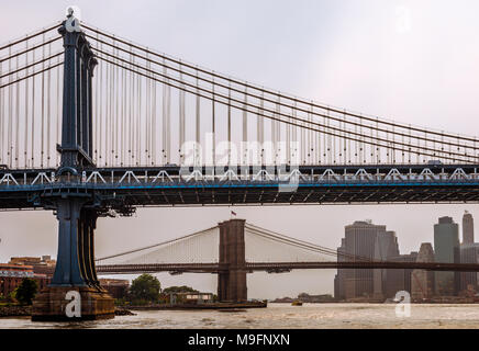 Ein Blick auf die Manhattan und Brooklyn Bridge an einem bewölkten Tag, in New York. Foto von der Fähre genommen, während der Kreuzfahrt East River. Stockfoto