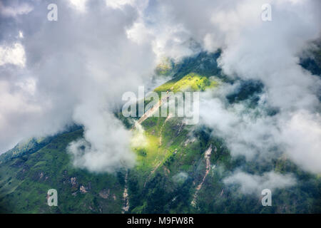 Berge mit grünen Wald in Wolken in bewölkten Tag im Sommer in Nepal. Landschaft mit schönen Hügel mit Bäumen und dramatische bewölkter Himmel bei Sonnenuntergang. Stockfoto