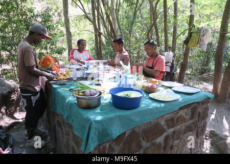 Eingeborene, lokale Leute aus Madagaskar sind die Mittagessen für Touristen in einem ruhigen Park. Stockfoto