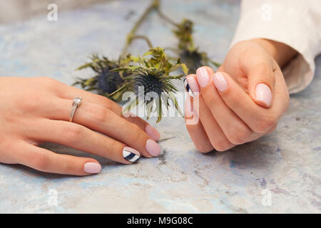 Nagel Konzept und Blumen. Schöne Maniküre. Rosa Schellack mit schwarzen und weißen Design. Kein Gesicht. Beauty Salon Lage. Stockfoto