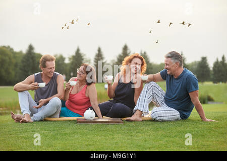 Fröhliche Paare im Park sitzen. Lächelnd senior Freunden Kaffee trinken und Spaß haben. Stockfoto