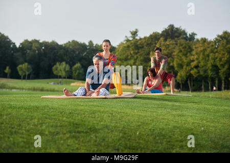 Gruppe Thai Massage im Sommer Park. Reife Menschen erhält für traditionelle thailändische Therapie für die Schultern. Stockfoto