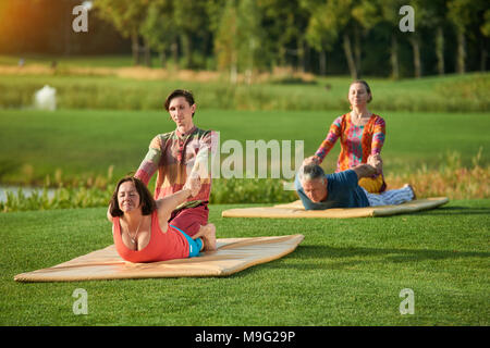 Thai Yoga Körperarbeit. Thai Massage in Cobra Position. Gruppe sport Übungen im Freien. Stockfoto