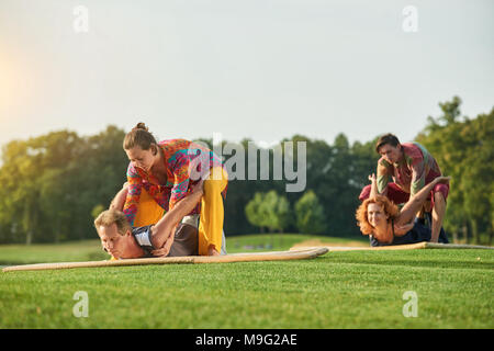 Yoga pose liegend auf Bauch. Gruppe Thai Massage auf dem Rasen. Stockfoto