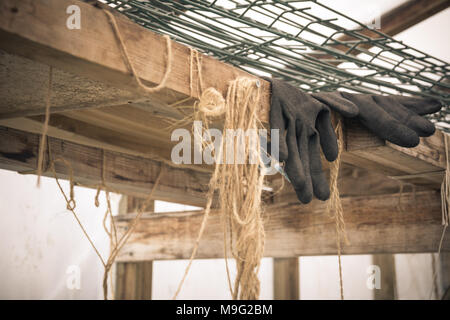 In der Nähe von Gummi Handschuhe eines Landwirts liegen im Gewächshaus. Harte Arbeit Konzept. Vintage Style. Stockfoto