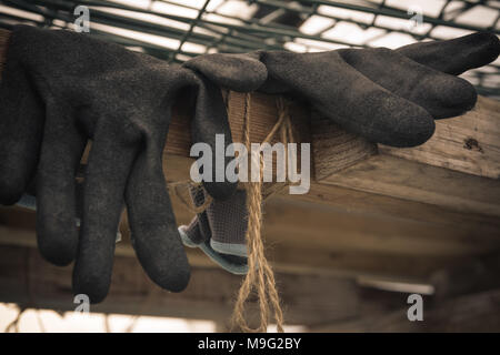 In der Nähe von Gummi Handschuhe eines Landwirts liegen im Gewächshaus. Harte Arbeit Konzept. Vintage Style. Stockfoto