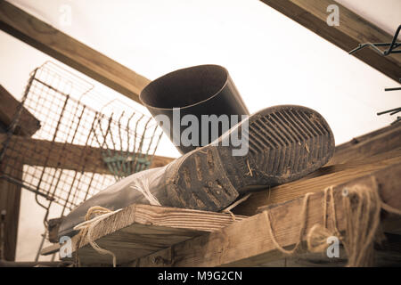 Gummistiefel von einem Bauern liegen im Gewächshaus. Harte Arbeit Konzept. Vintage Style. Stockfoto