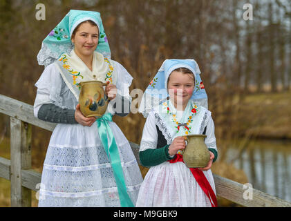 Abbildung - 24 März 2018, Deutschland, Schlepzig: Zwei Schwestern Aliena (L) und Leonie Huber zeigt in Sorbischen und Wendischen festliche Tracht in einem geschlechtsgeruches Szene der Lausitz brauch Osterwasser holen am Fluss Spreewald Dorf Schlepzig. Frauen und Mädchen gehen mit Tonkrüge zu einem Fluß und Wasser in der Nacht holen vor dem Ostersonntag. Auf dem Weg dorthin und zurück keine Worte gesprochen werden. Das Wasser hat eine besondere magische Kraft die Auszeichnung Schönheit und Gesundheit. Foto: Patrick Pleul/dpa-Zentralbild/ZB Stockfoto