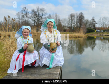 Abbildung - 24 März 2018, Deutschland, Schlepzig: Zwei Schwestern Aliena (L) und Leonie Huber zeigt in Sorbischen und Wendischen festliche Tracht in einem geschlechtsgeruches Szene der Lausitz brauch Osterwasser holen am Fluss Spreewald Dorf Schlepzig. Frauen und Mädchen gehen mit Tonkrüge zu einem Fluß und Wasser in der Nacht holen vor dem Ostersonntag. Auf dem Weg dorthin und zurück keine Worte gesprochen werden. Das Wasser hat eine besondere magische Kraft die Auszeichnung Schönheit und Gesundheit. Foto: Patrick Pleul/dpa-Zentralbild/ZB Stockfoto