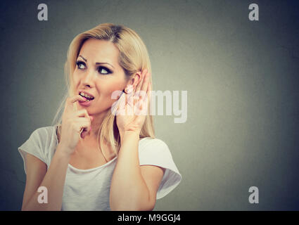 Junge hübsche Blondine die Hand in der Nähe von Ohr versucht, Gerüchte zu fangen, während das Abhören. Stockfoto