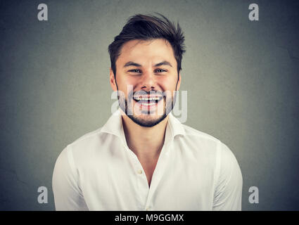 Junger bärtiger Mann im eleganten weißen Hemd an Kamera und aufgeregt zu lachen. Stockfoto