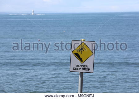 Eine gelbe Gefahr tiefen drop Schild warnt die Menschen gegen das in der Nähe einer steilen Klippe an der Westküste von Irland. Stockfoto