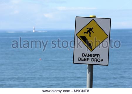 Eine gelbe Gefahr tiefen drop Schild warnt die Menschen gegen das in der Nähe einer steilen Klippe an der Westküste von Irland. Stockfoto