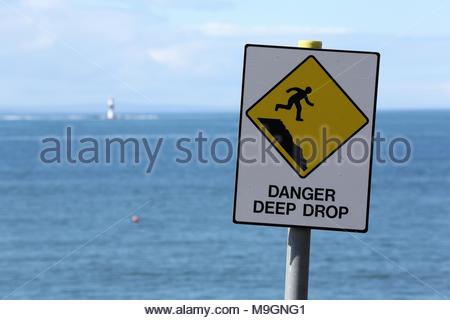 Eine gelbe Gefahr tiefen drop Schild warnt die Menschen gegen das in der Nähe einer steilen Klippe an der Westküste von Irland. Stockfoto