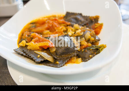 Teller schwarz Tintenfisch Ravioli mit Tomatensauce. Selektiver Fokus Stockfoto