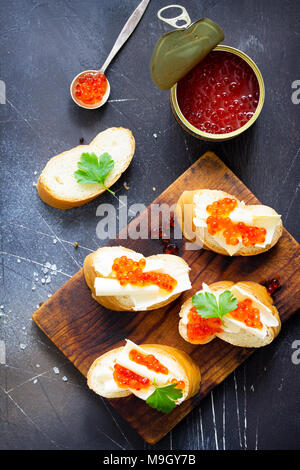 Festliche Snack. Sandwiches mit rotem Kaviar, auf dunklen konkreten Hintergrund isoliert. Stockfoto