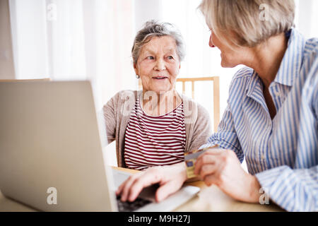 Nicht erkennbare ältere Frau mit ihrer Mutter mit Laptop zu Hause. Familie und Generationen Konzept. Stockfoto