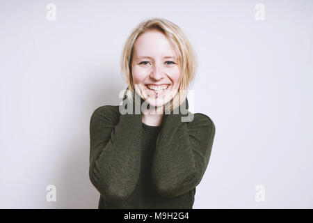 Gerne blonde junge Frau mit toothy Lächeln Stockfoto