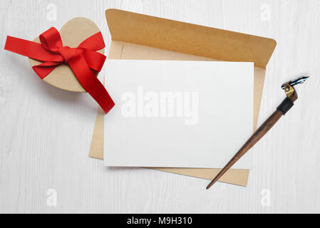 Mockup kalligrafische Feder einen Umschlag mit Brief und ein Geschenk mit roter Schleife, Grußkarten für Valentines Tag mit Platz für Ihren Text. Flach, Ansicht von oben Foto Mock up Stockfoto