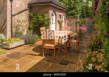 Design & Garten mit gepflasterten Terrasse, Rankgitter, Tisch & Stühle durch die Hintertür von Kunst & Handwerk Haus - West Yorkshire, England, UK. Stockfoto