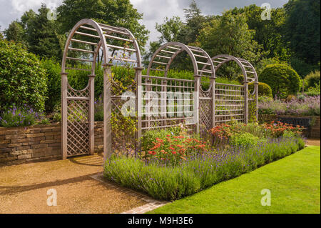 Sommer Blick auf die sonnenbeschienenen Tunnel Laube & bunten Blumenrabatten - Schöne, gestaltet, gepflegten, traditionellen Garten, West Yorkshire, England, UK. Stockfoto