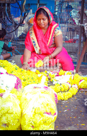 Eine weibliche florist Vorbereitung Girlanden in einem lokalen Markt von New Delhi, Indien. September 29, 2017. Stockfoto