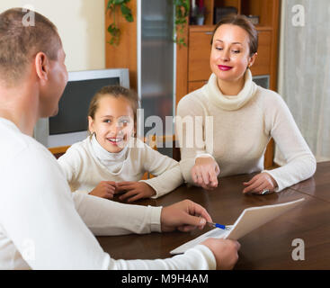 Eltern und lächelnd kleine Tochter beantworten Fragen von Übertreffenarbeiter zu Hause Stockfoto